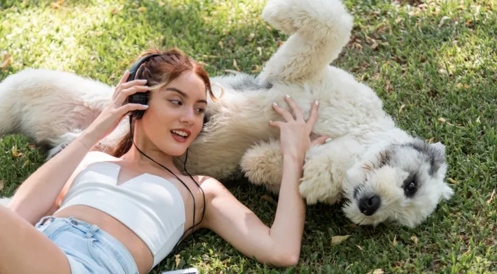 Pretty girl and a dog rolling in poop in a park